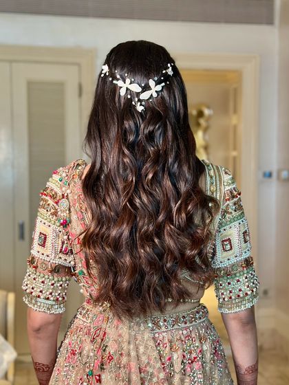 A view of the beautiful, soft waves and butterfly hair accessory. The hairstyle perfectly complements the romantic and elegant feel of the engagement look.