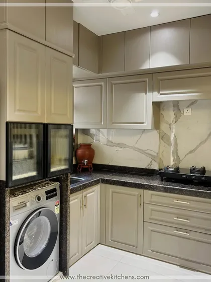 This kitchen demonstrates how to create a cohesive and elegant space with a neutral color palette. The warm, earthy tones of the routed cabinets are complemented by a striking marble-patterned backsplash and dark granite countertop.