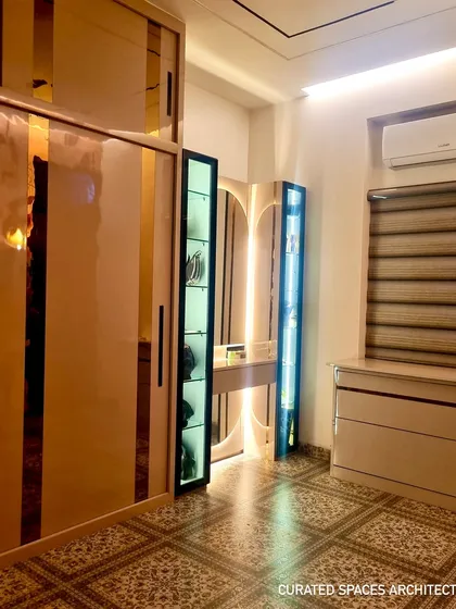 A wider view of the closet room, showcasing the spacious sliding wardrobe with reflective panels, the custom vanity, and the stylish patterned floor tiles.