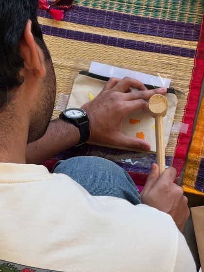 A participant focused on creating his design on a canvas pouch. Flower pounding is an engaging activity for everyone, offering a chance to disconnect from stress and connect with creativity.