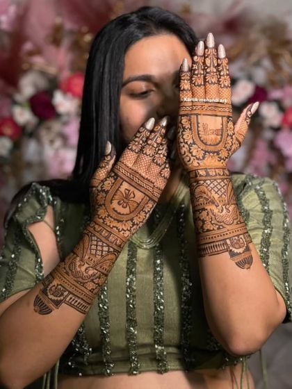 A bride showing her beautiful back-hand mehandi. The design features a mix of traditional motifs and modern patterns, creating a unique and personalized look.
