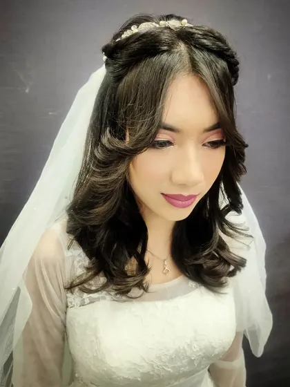 This profile view of a Christian bridal look demonstrates the soft waves and elegant hair-updo taught in our hairstyling module, complete with a delicate tiara and veil placement.