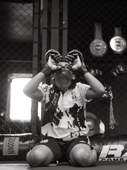 A young fighter performs the Wai Kru, a ritual of respect. This moment of focus before training or a fight connects the warrior to their teachers and the spirit of Muay Thai.