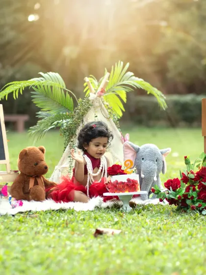 A wide shot of the adorable picnic setup for a second birthday. The teddy bear and elephant join the party, creating a whimsical scene for this outdoor cakesmash.