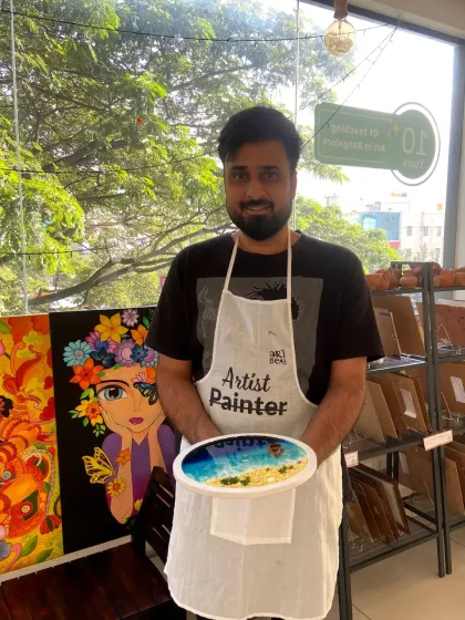 A participant proudly shows off his finished resin beach art, complete with sandy textures and rolling waves. You don't need any experience to walk out with a piece this beautiful.