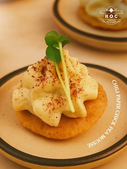 We delight in reimagining classic flavours. This is our Chilli Papdi with Chickpea Mousse, a bite-sized appetizer that combines the crispness of a traditional snack with a smooth, gourmet mousse, offering a surprising and sophisticated taste.