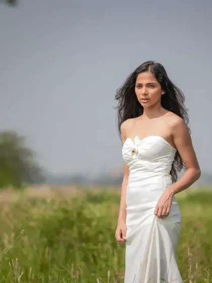 A full-length editorial shot of the bride in a field. The composition and her confident stance give this a high-fashion, magazine-spread feel.