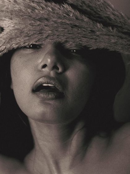 A bold and unconventional composition in black and white. The pampas grass covers the top of the model's face, drawing all attention to her mouth and expression. It's an artistic and intriguing shot.