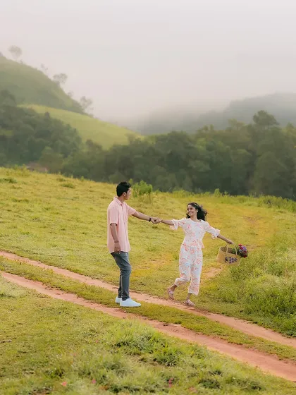A playful, dancing moment on a hilltop path. The vast, misty landscape of the Western Ghats provides a stunning backdrop.