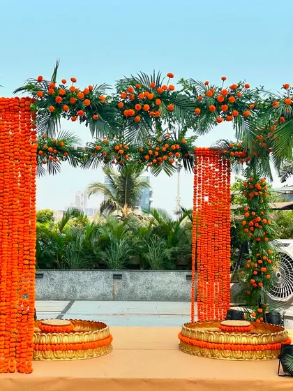 A vibrant Haldi mandap on a terrace, using bright orange marigolds to create a stunning structure against the city skyline.
