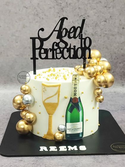 A Moët & Chandon champagne cake that's "Aged to Perfection." This celebratory cake is decorated with an edible champagne bottle, a glass, and shimmering gold bubbles.