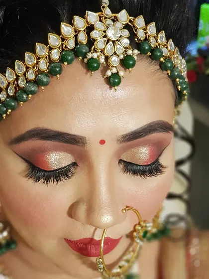 Eyes are my canvas. This close-up shows a detailed cut crease with warm red and shimmering gold tones, finished with dramatic winged eyeliner. I customize every eye makeup look to suit the bride's eye shape, outfit, and personal style.