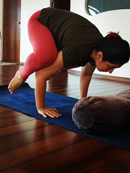 A student using a bolster as a prop to build confidence in her crow pose. Props are amazing tools for learning, and I encourage using them.