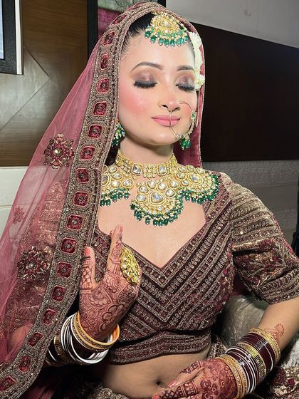Two portraits of a bride in a deep wine-colored lehenga, focusing on the detailed blouse and the heavy emerald jewellery. Excellent for MUA and jewellery styling inspiration.