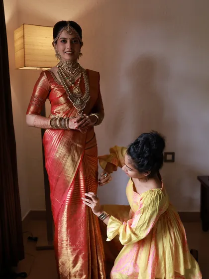 A behind-the-scenes moment, perfecting the pleats on a beautiful red silk saree. Every fold is a step towards creating bridal magic.