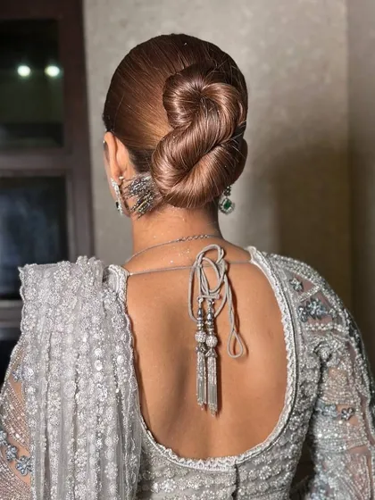 A bridal look isn't complete without the perfect hairstyle. This sleek, intricate bun is a timeless choice that is both elegant and secure, ensuring your hair looks flawless from the first photo to the last dance.