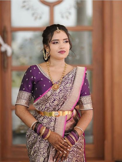 This client is wearing a beautiful brocade saree in shades of purple and gold, paired with a custom deep purple blouse with border detailing on the sleeves.