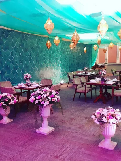 This is a lounge and dining area I designed for a pre-wedding event. The combination of teal fabric draping, Moroccan-style lanterns, and floral urns creates a relaxed yet stylish ambiance for guests to mingle.