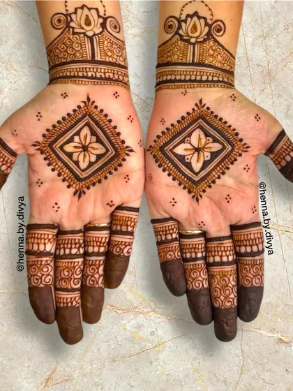 This design features a bold, diamond-shaped geometric motif on the palm. Paired with a lotus cuff, it's a powerful and modern design that makes a statement.