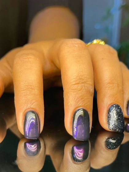 A chic manicure combining purple cat-eye nails with a sparkling black glitter accent nail.