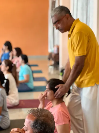 A teacher gives a gentle correction to a student during a pranayama class. This ensures the student maintains the correct posture for optimal energy flow.
