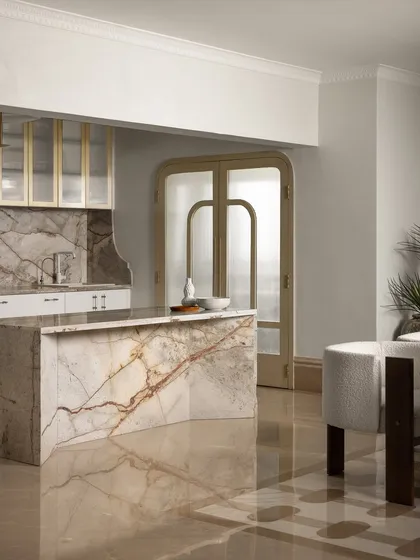 This breakfast island and kitchen is a study in quiet luxury, where a sculptural marble island takes center stage. We balanced the strength of the stone with golden-framed glass cabinets and curved door frames, creating a space that feels as effortless as it is elegant.