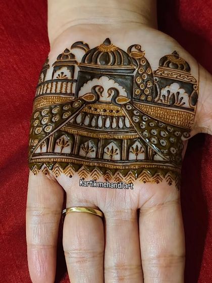 A small but intricate trial piece for a palm, featuring a palace scene with swans and peacocks. This helps clients visualize the final look.