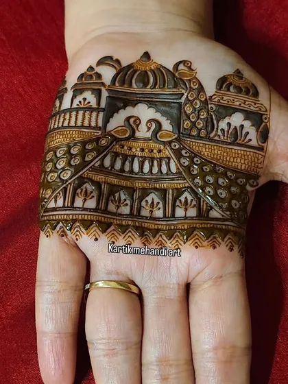 A small but intricate trial piece for a palm, featuring a palace scene with swans and peacocks. This helps clients visualize the final look.
