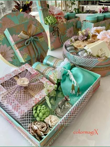 A detailed view of a coordinated gift set in our signature teal floral print. This image displays a gift box, a round basket, and smaller items, all featuring intricate details like lace, ribbons, and handcrafted flowers.
