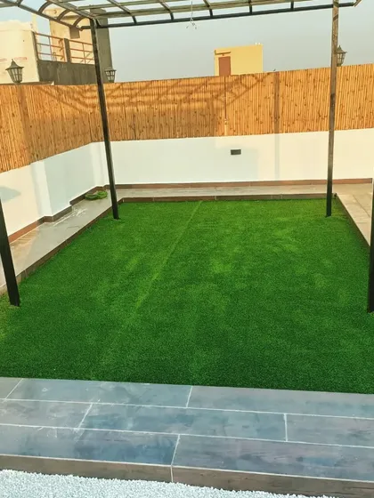A simple yet effective terrace design. We installed an artificial turf area under a minimalist pergola, bordered by a bamboo screen for privacy and a bed of white pebbles for a clean finish.