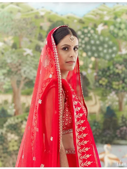 A stunning bridal portrait. The bride's direct gaze is powerful, and the vibrant red of her veil contrasts beautifully with the soft, artistic background. I aim to capture the strength and beauty of every bride on her special day.