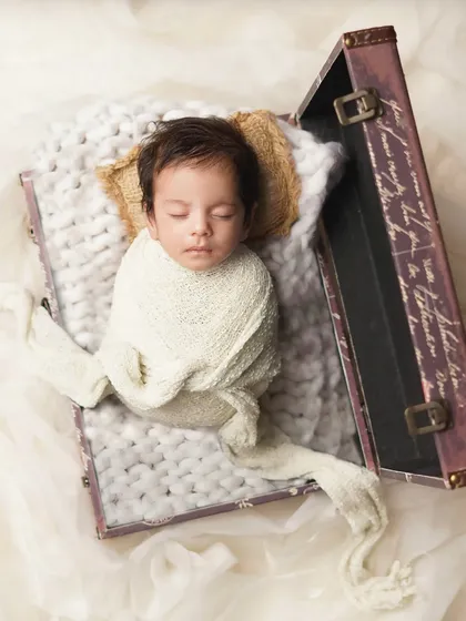 A wider shot showing the newborn swaddled and tucked into an open suitcase, as if he's the most precious cargo. This is a fun concept for a travel-themed baby announcement.