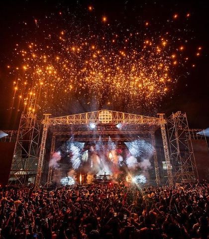 The full scale of the Sunburn Arena with Armin van Buuren, complete with a massive stage, a huge crowd, and a sky full of fireworks.