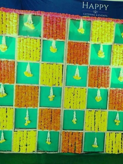 Another variation of the popular chequered flower backdrop, this time using orange and yellow marigolds against a green background. The hanging jasmine buds add a fragrant and delicate detail to the design.