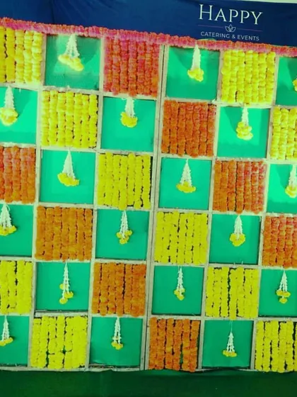 This traditional backdrop uses a checkerboard pattern of marigold garlands in orange, yellow, and green. It's a classic and colorful choice for any auspicious occasion.