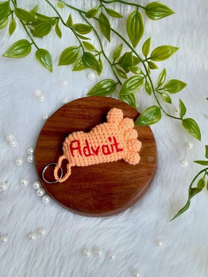 The 'Advait' baby foot keychain on a wooden disc.