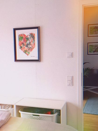 My custom Tiranga heart painting, framed and hung in a client's home. It adds a pop of color and personal meaning to this bright, modern room. You can see how it fits beautifully into the corner of this space.