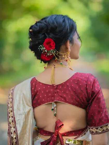 A back view of the intricate khopa hairstyle, adorned with fresh red roses that match her blouse. Every detail is thoughtfully curated.
