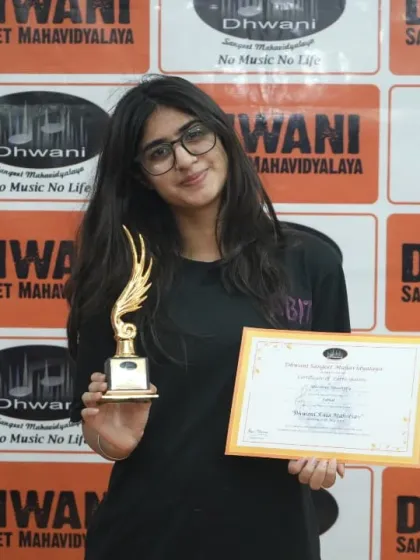A student proudly holds her certificate and trophy.