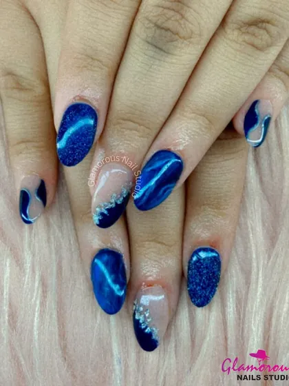 Dive into the deep blue with this mesmerizing set. We combined a sparkling blue glitter nail, a deep blue cat-eye effect, and abstract designs with silver accents for a look that is full of depth and texture.