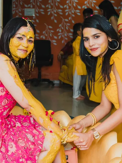 A friend applying Haldi to the bride, a traditional and intimate moment of the pre-wedding rituals.