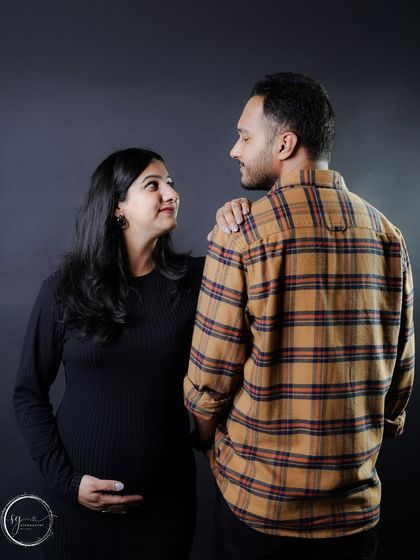 A candid moment of conversation and connection between the couple, captured against a simple dark background for a dramatic effect.