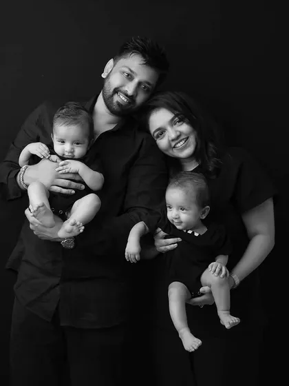 A classic family portrait with twins. The parents each hold a baby, creating a beautiful, balanced composition full of joy.