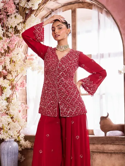 A full-length shot of the vibrant red outfit. The makeup is glamorous yet refined, ensuring it enhances the overall look without competing with the detailed embroidery.