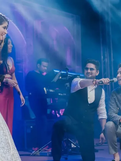 A serenade for the happy couple. The groom gets down on one knee as a live singer performs on stage, creating a romantic and interactive moment during their grand Sangeet at the Taj Lands End.