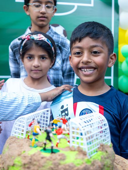 The birthday boy smiles brightly, excited for his football-themed cake and celebration.