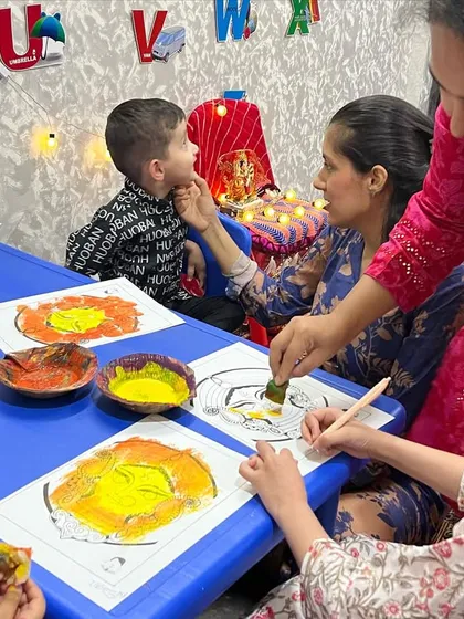 A mother helps her child with a sponge painting of Maa Durga's face during our festive workshop. It's a wonderful parent-child bonding activity.
