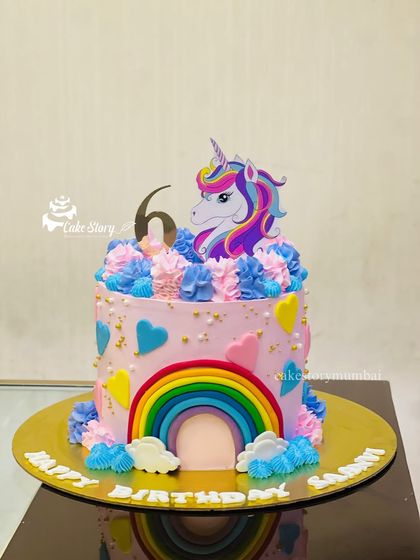 A vibrant unicorn and rainbow cake for Saanvi's 6th birthday. This pink cake is decorated with buttercream swirls, hearts, and a colorful rainbow arch.