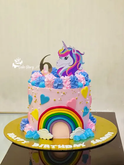 A magical unicorn and rainbow cake for a 6th birthday. The colorful rainbow arching over the cake and the pretty unicorn topper make it a bright and cheerful centerpiece.