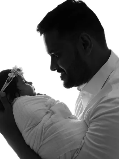 A striking black and white silhouette of a father holding his newborn baby.